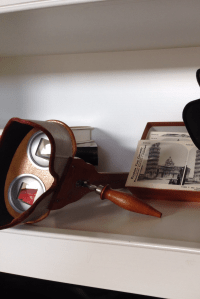 A poorly cropped photo of a stereoscopic viewer with a stereo photo of the Leaning Tower of Pisa in the background.